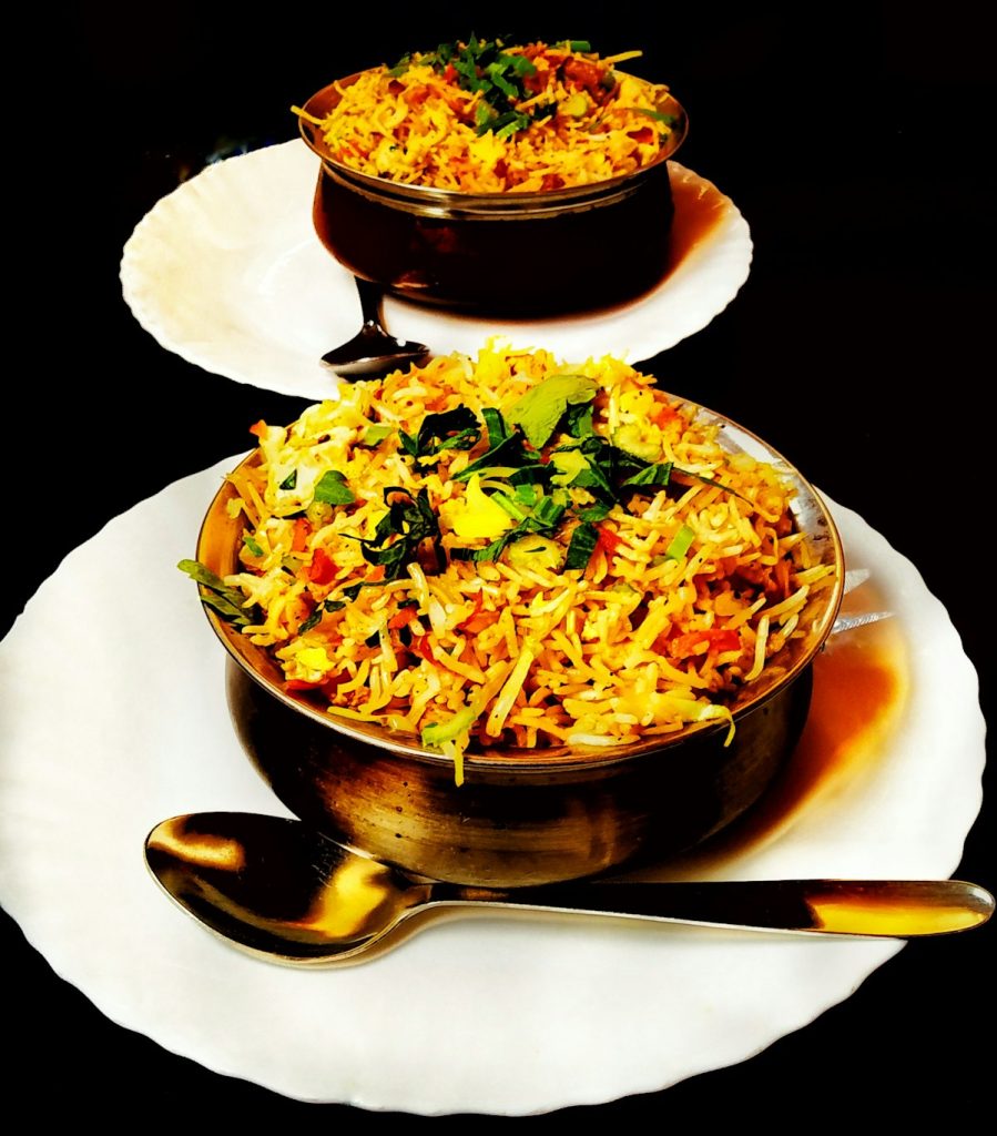 Bowl of biryani garnished with herbs, served with raita