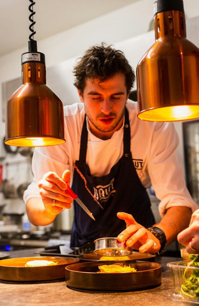 Cook preparing food at the pass with focused attention
