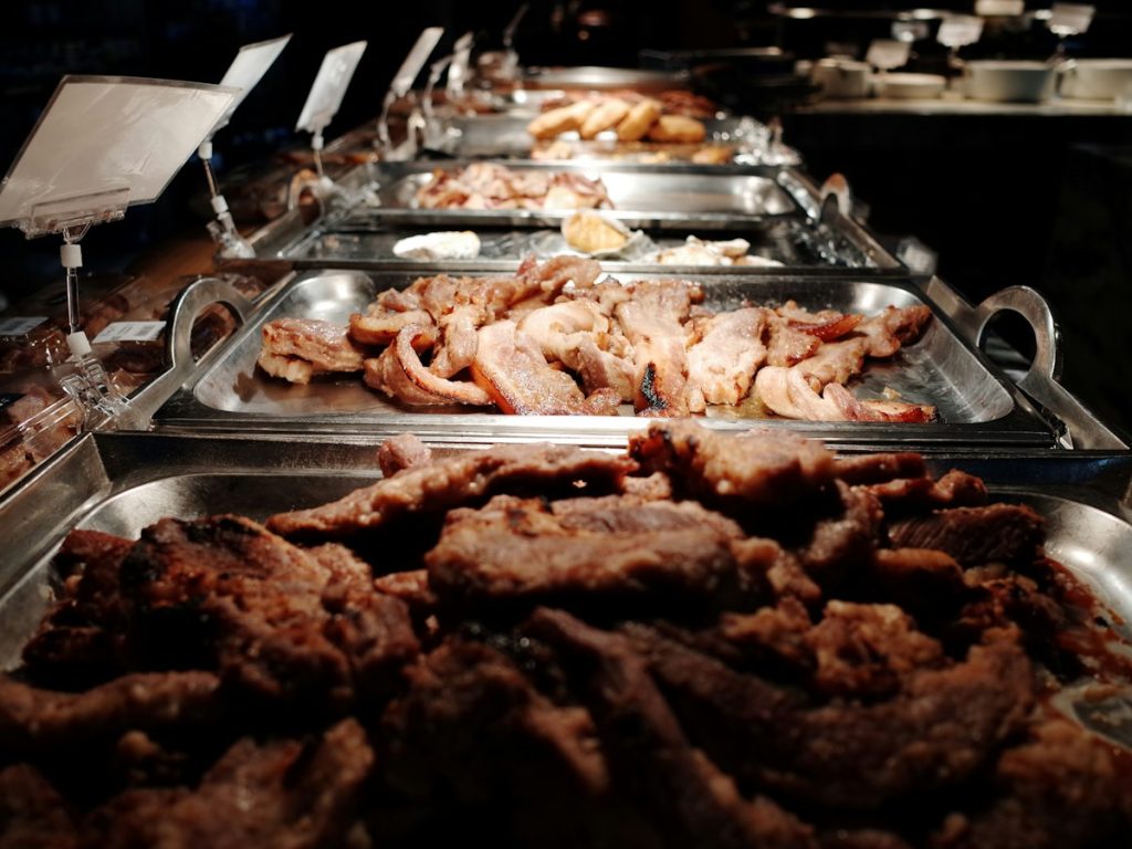 Trays of grilled meat ready in a catering chafing line
