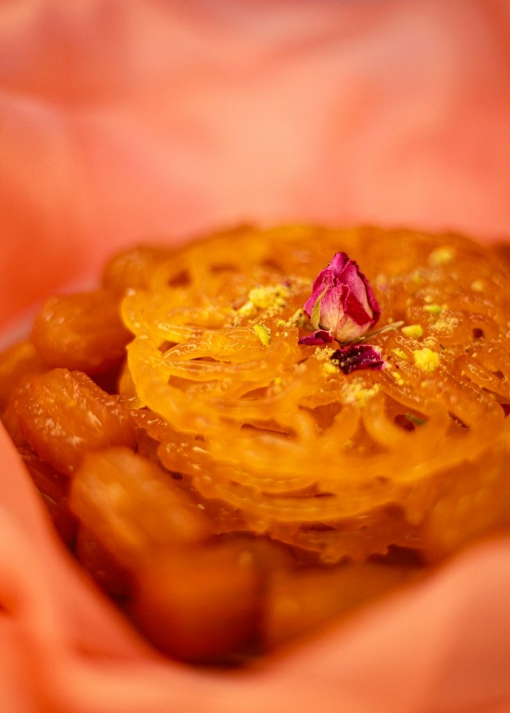 Syrupy jalebi garnished with rose petals and pistachio