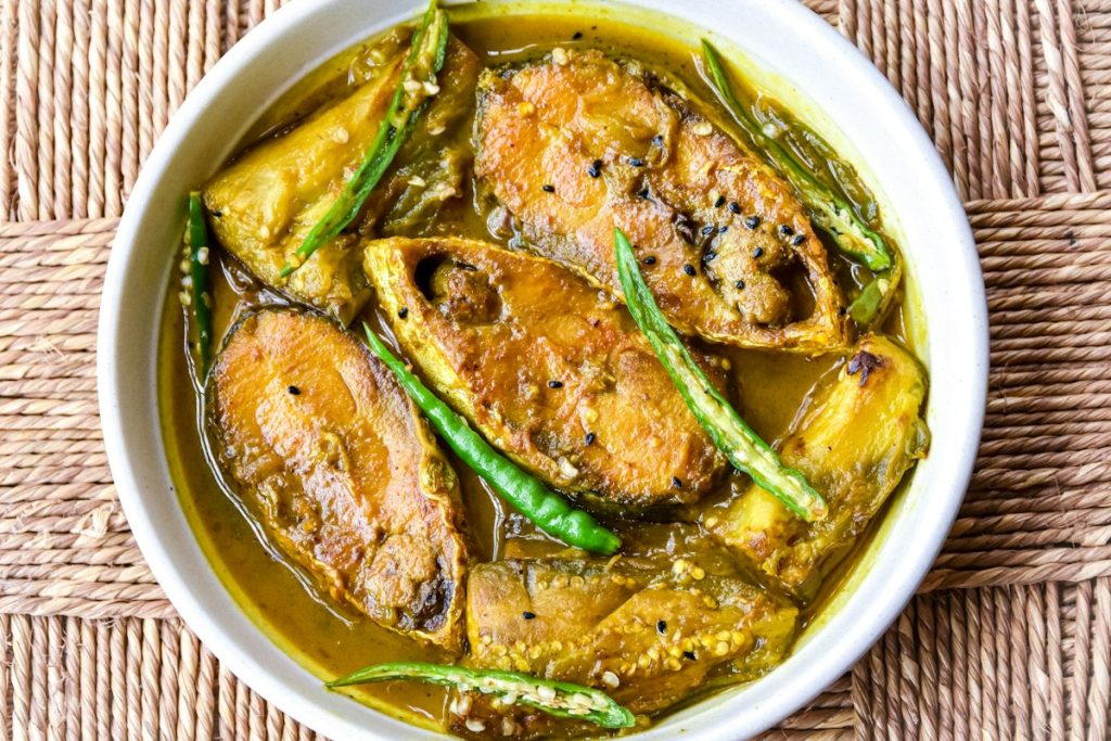 Shorshe ilish — hilsa fish cooked in mustard gravy with green chillies