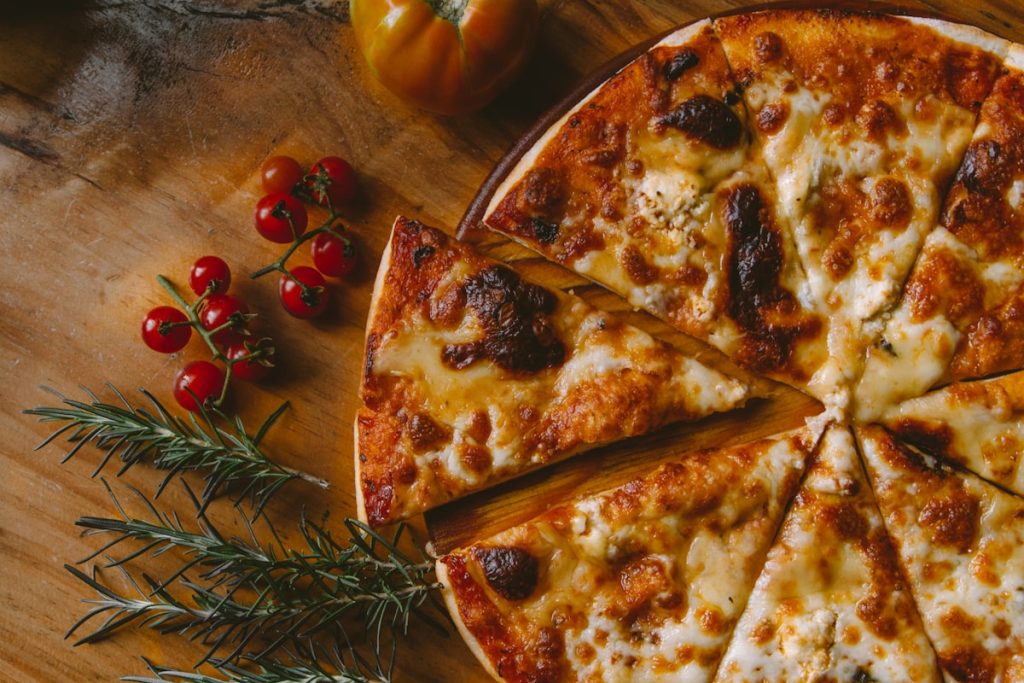 Sliced stone-baked pizza with cherry tomatoes on a wooden board
